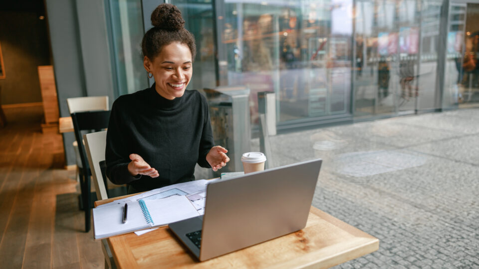 Frau im Videocall für eine Bewerbung. In einem Cafe sitzend am Fenster.