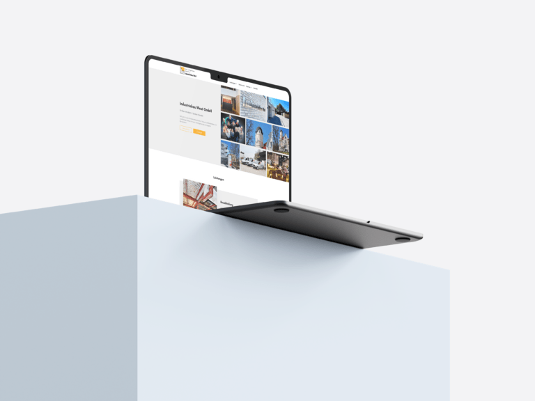 Ein aufgeklappter Laptop steht auf einem weißen Block, auf dem die Internetseite von Industriebau West zu sehen ist.